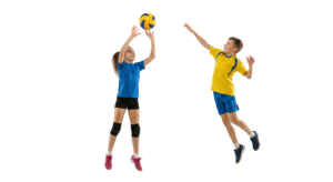Boy and Girl Playing Volleyball Jumping to Hit Ball